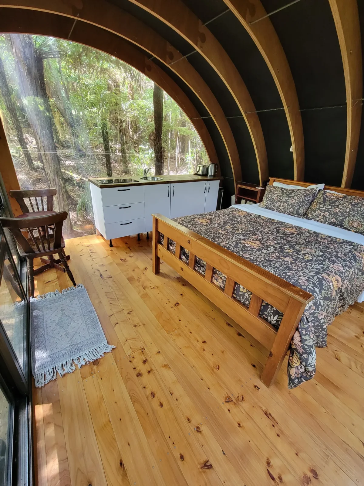 Bedroom with wooden floors and arched ceiling in the Forest Cabin at Totara Enclave
