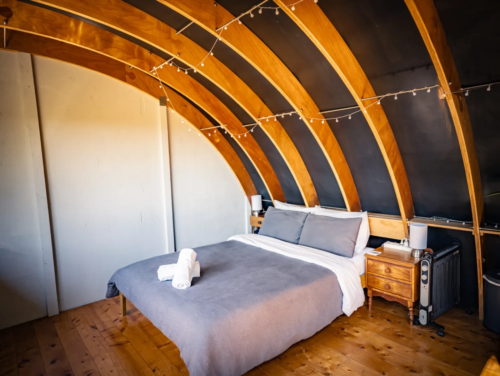 Bedroom with arched ceiling and timber floors in The Outpost cabin at Totara Enclave"