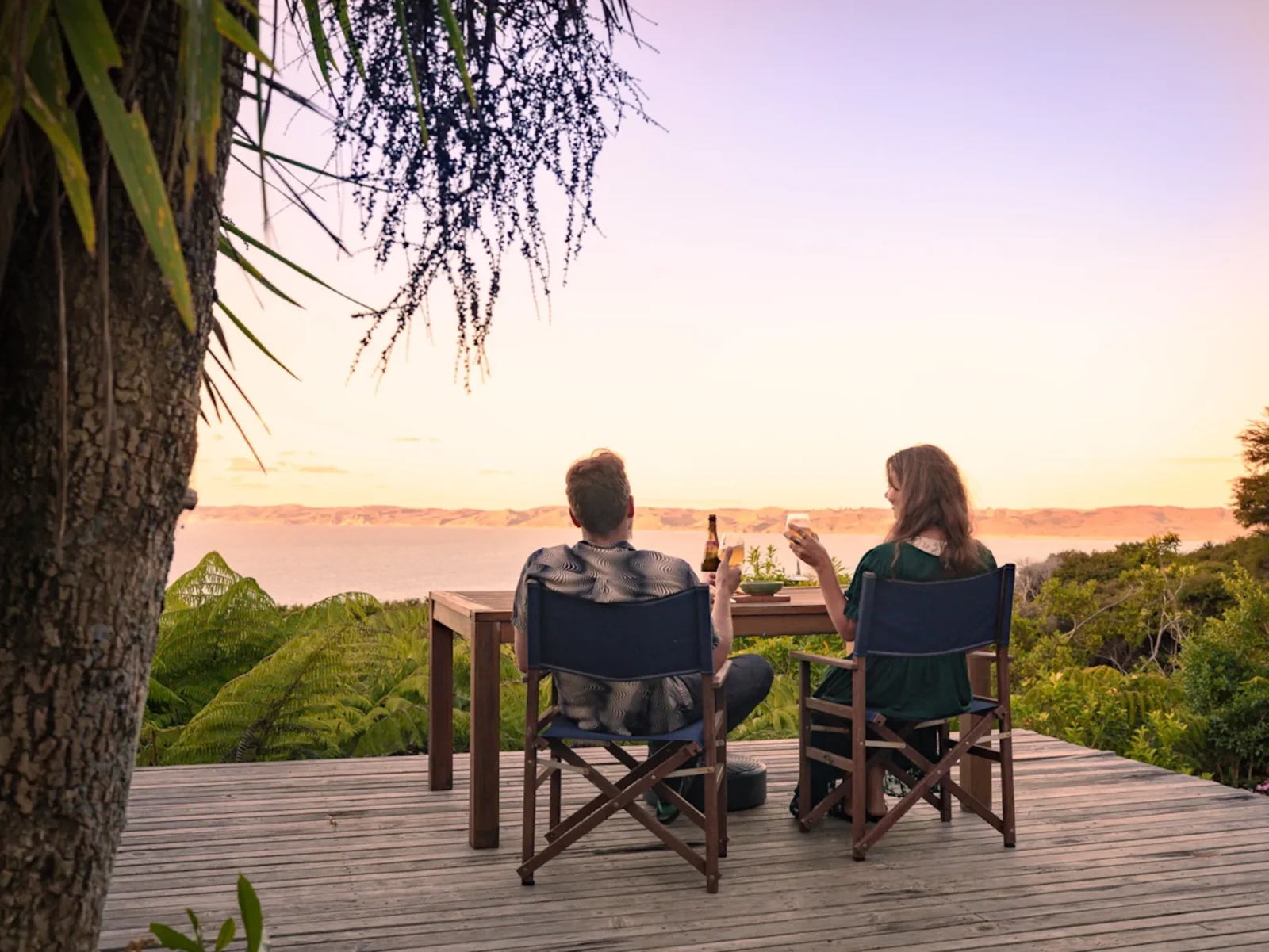 Couple enjoying drinks on the deck at sunset at Totara Enclave